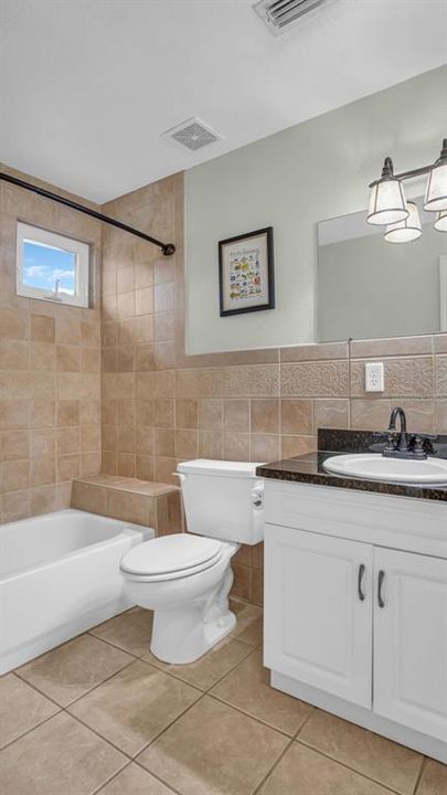 Primary suite bathroom, featuring dual corner vanities, granite countertops, updated plumbing and lighting fixtures, large soaking tub, and separate shower