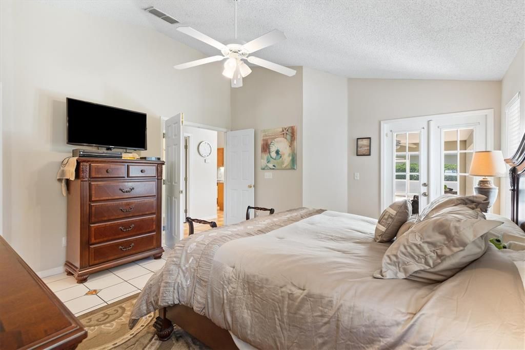 Spacious primary bedroom with French doors leading out to pool and covered & screened lanai