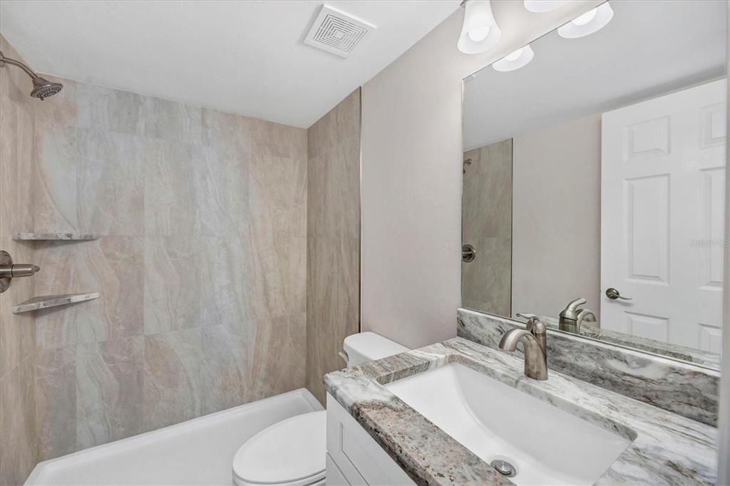 Guest bathroom - wood cabinets, granite, tile