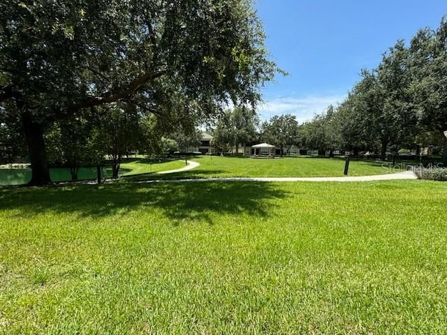 A covered, screen patio overlooks a beautiful and relax green area with the community pool just beyond.