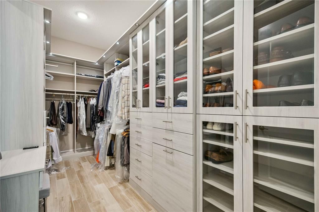 custom primary bedroom walk-in closet with built-ons and lighting