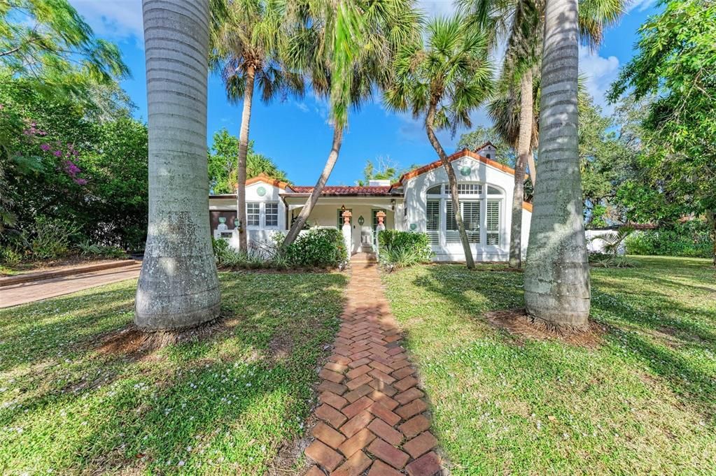 Royal Palms frame the walkway leading to the cottage. Orange jasmine and hibiscus trees among other native Floridian vegetation enhance the curb appeal of this adorable home.
