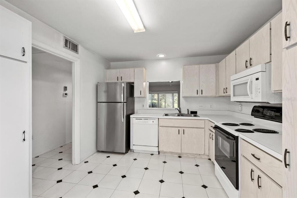 Spacious kitchen featuring ample cabinetry, laundry, a dinette, and direct access to the front courtyard.