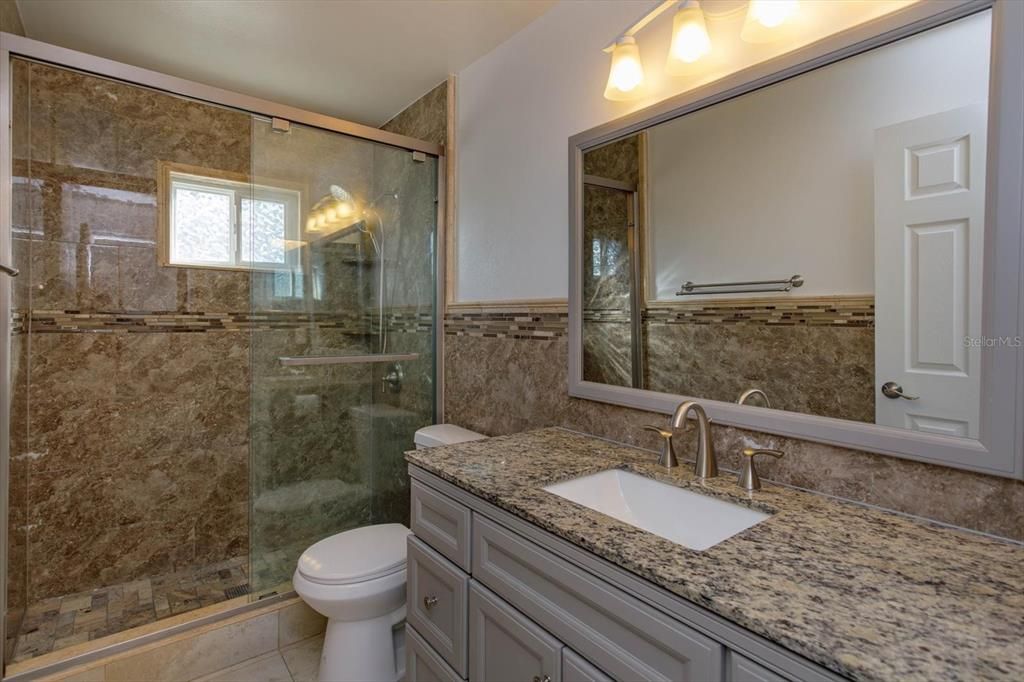 Luxury hall bath with new vanity, granite counters, new shower w/glass enclosure, and new toilet.