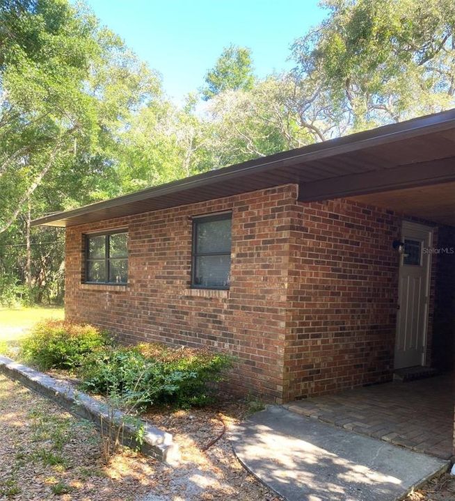 Attractive rustic brick and wood covered Breezeway that runs along side of main house and guest apartment