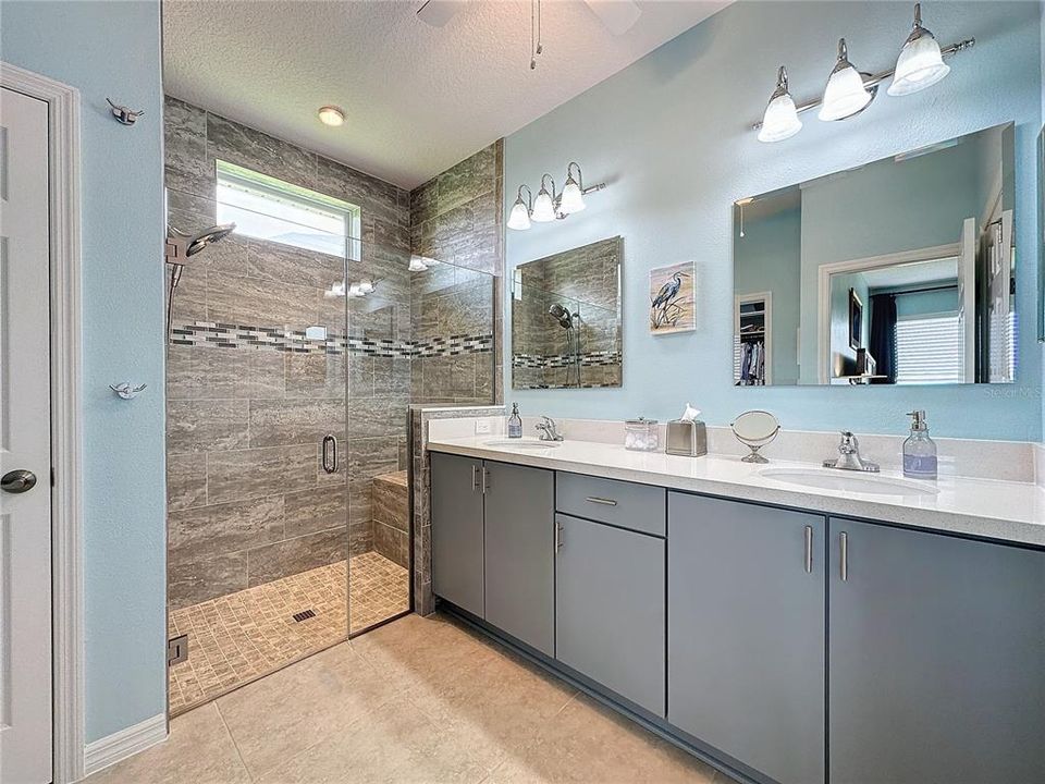 Primary bathroom - Dual, elevated sink vanities, frameless glass enclosed upgraded and modern tiled shower with bench
