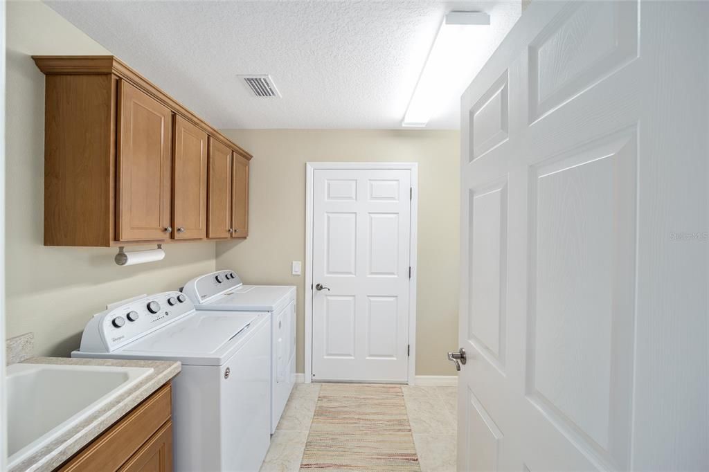 The laundry room has cabinets and a sink.  The closed door leads to the garage.