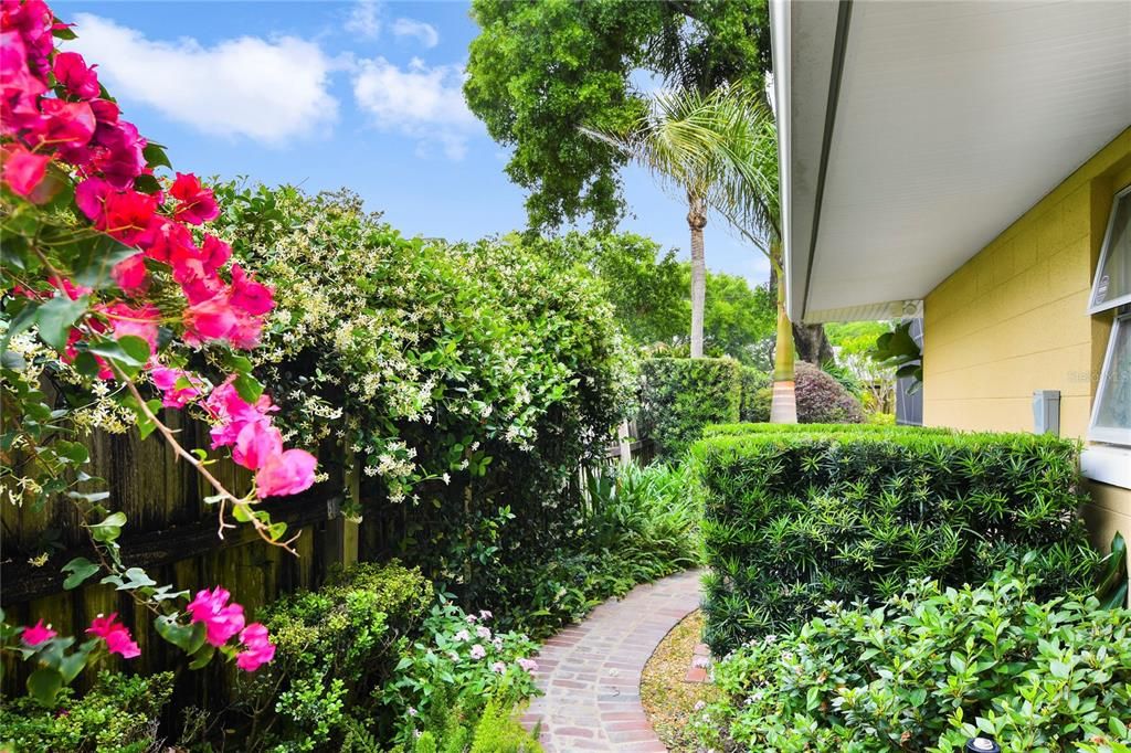 Lush landscaping with a brick walkway leading to the backyard.