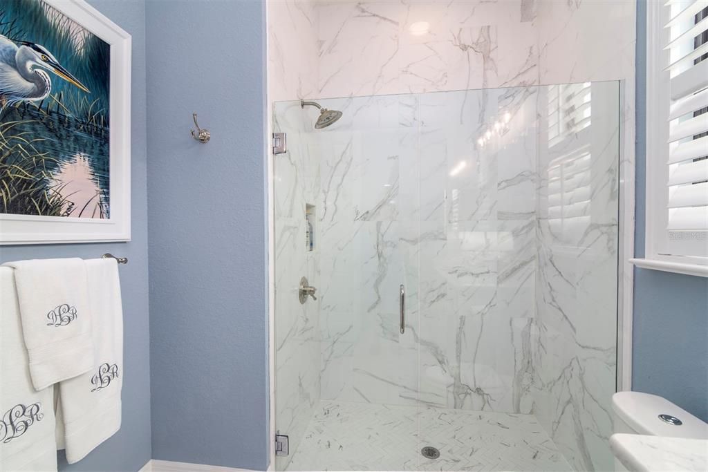 The stall shower in the guest bathroom has a glass shower door and enclosure.