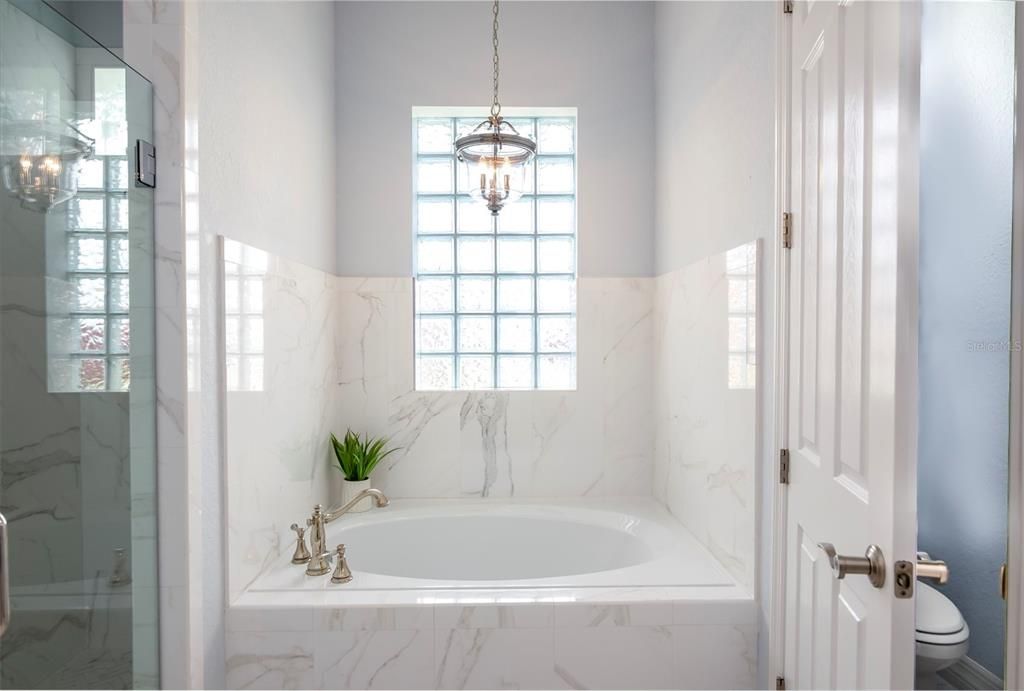 The master bath has a garden tub. The glass block window allows light, but provides privacy. The privacy toilet area and stall shower are on either side.