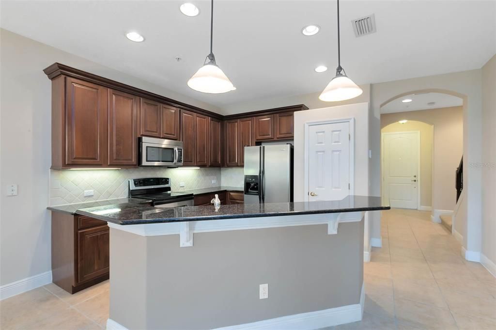 The beautiful kitchen boasts 42” maple cabinets, granite countertops, a granite-topped breakfast bar, tile backsplash, and stainless steel appliances