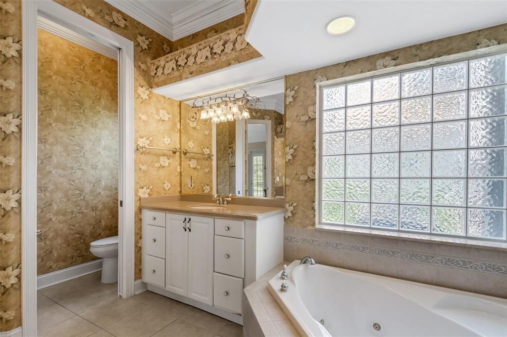 The primary bath has split his & her vanities, spa tub, private commode, and walk-in shower.