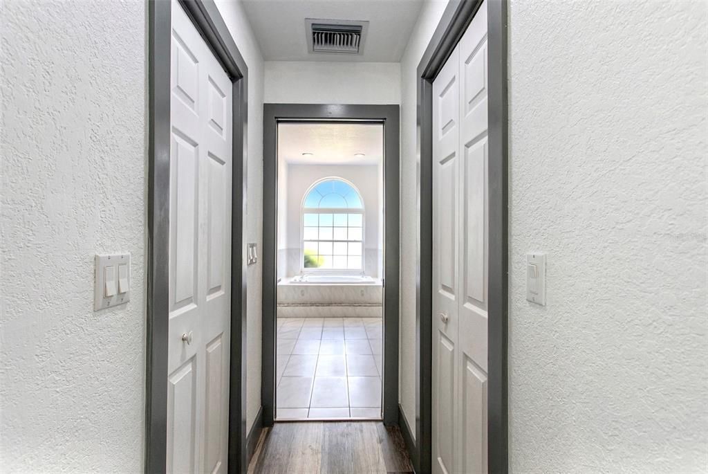 Two walk-in closets flank the hallway, leading you to a luxurious master bathroom. A peek of a gorgeous Mediterranean window and the sparkling jacuzzi, hinting at the spa-like retreat that awaits.