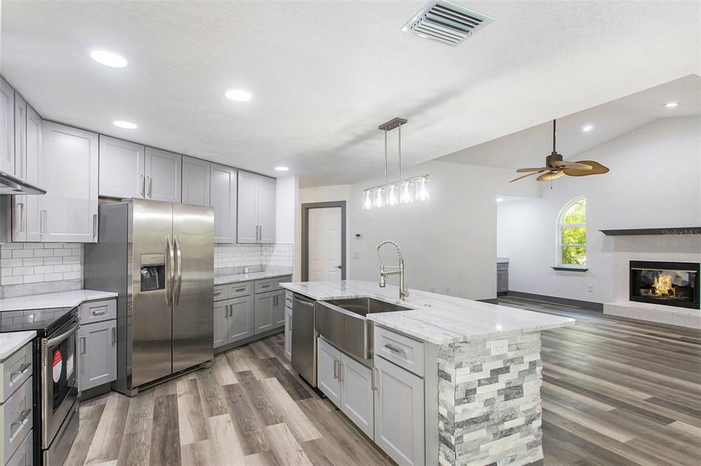 Kitchen designed for entertaining! The open concept layout seamlessly integrates with the inviting fireplace, wet bar, and the rest of the living space, creating a perfect haven for relaxation and connection.