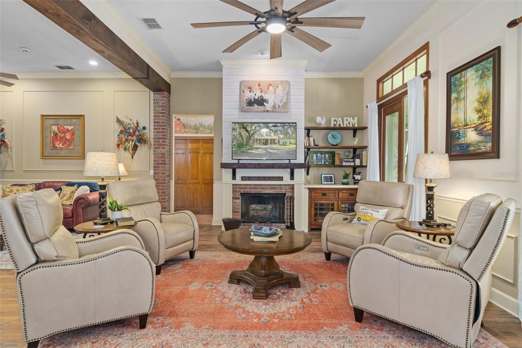 Family room with wood burning fireplace. Wood beams and brick columns