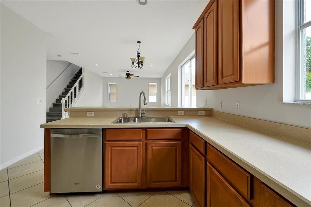 Kitchen with golden oak cabinets, dishwasher, range, microwave and refrigerator.  Bright open window provides view of rear private yard with plenty of room for pool.