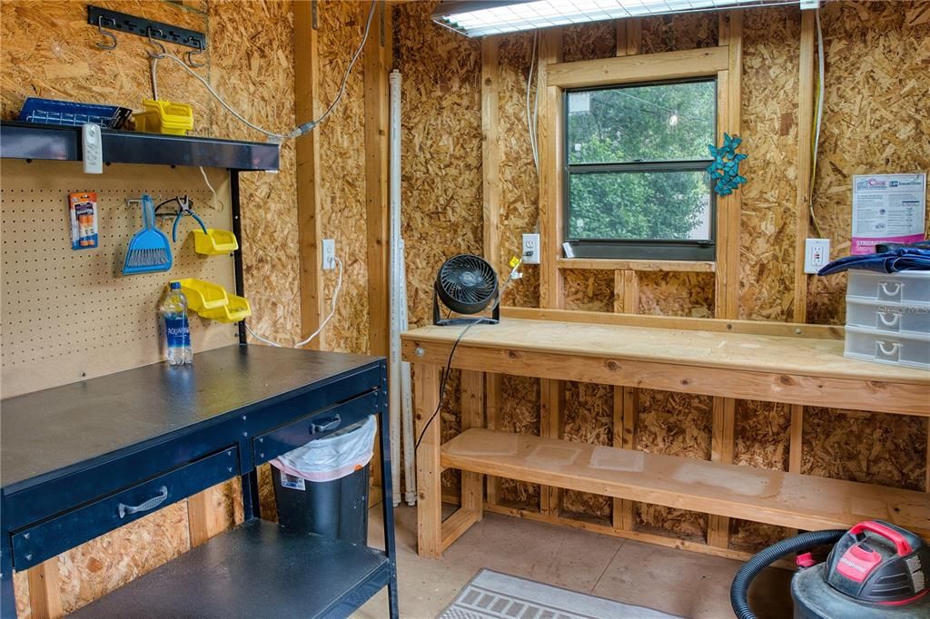 Inside the shed, a workbench, window, and adequate lighting create a functional and inviting workspace, suitable for a variety of projects and hobbies.