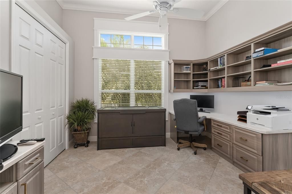 BEDROOM 3 (front) features 12' CEILINGS w/ CROWN MOLDING, specialty woodworking trim around TRANSOM WINDOW & window below, WOOD CORNICE on lower window, BUILT-IN desk & cabinets, CLOSET w/ overhead display ledge, & continuation of DIAGONAL SET, TILE FLOOR as well as CROWN MOLDING.