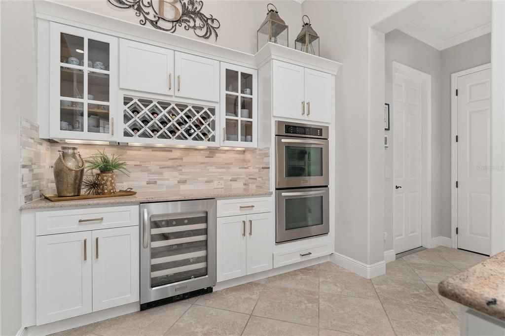 Close up view of WINE REFRIGERATOR, overhead wine rack, & DOUBLE WALL OVENS. Note GARAGE access door (R).