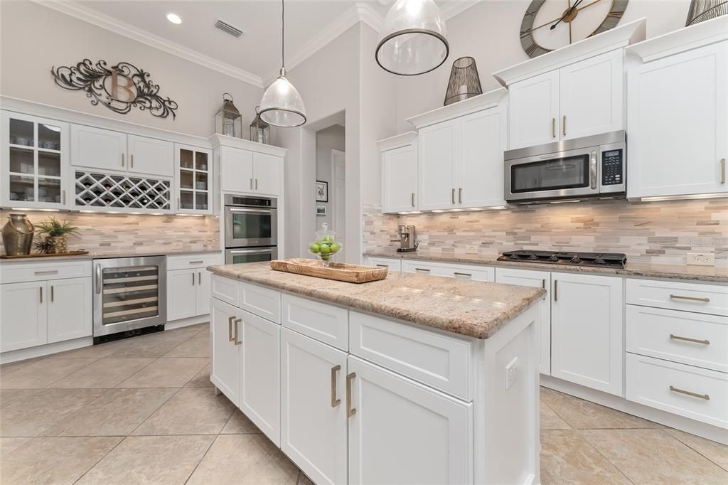 KITCHEN features UPGRADED SS APPLIANCES - GAS STOVETOP, MICROWAVE HOOD, DOUBLE WALL OVENS, WINE REFRIGERATOR, & French Door REFRIGERATOR (L) not visible fom this angle.