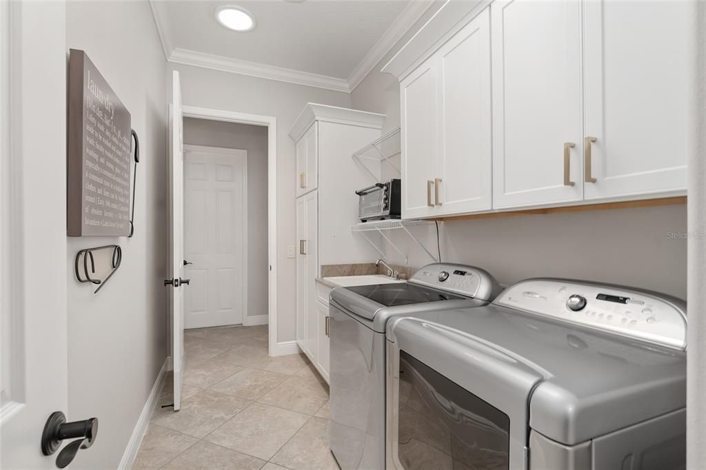 LAUNDRY ROOM has abundant storage cabinets.  Note: Access door to 3 car garage (center back).