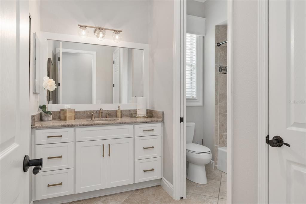 BATHROOM 2 is situated between BR 3 (front) & BR 2 (back) and features a GRANITE COUNTERTOP. A TUB/SHOWER COMBO w/ TILE SURROUND & COMFORT HEIGHT TOILET are hidden behind a POCKET DOOR.