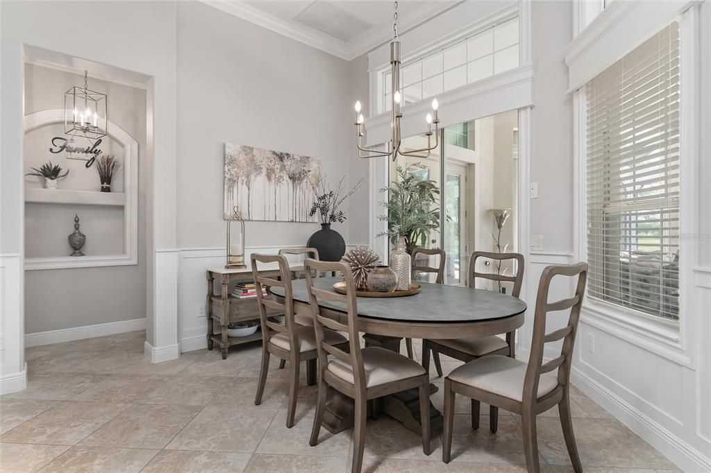 View of BREAKFAST ROOM shows custom WOOD PANELING & woodworking trim under the CHAIR RAIL. Note extensive woodworking trim around all windows & SLIDING GLASS DOORS as well. Hallway (L) leads to PRIMARY BR (R) & LAUNDRY ROOM (L).