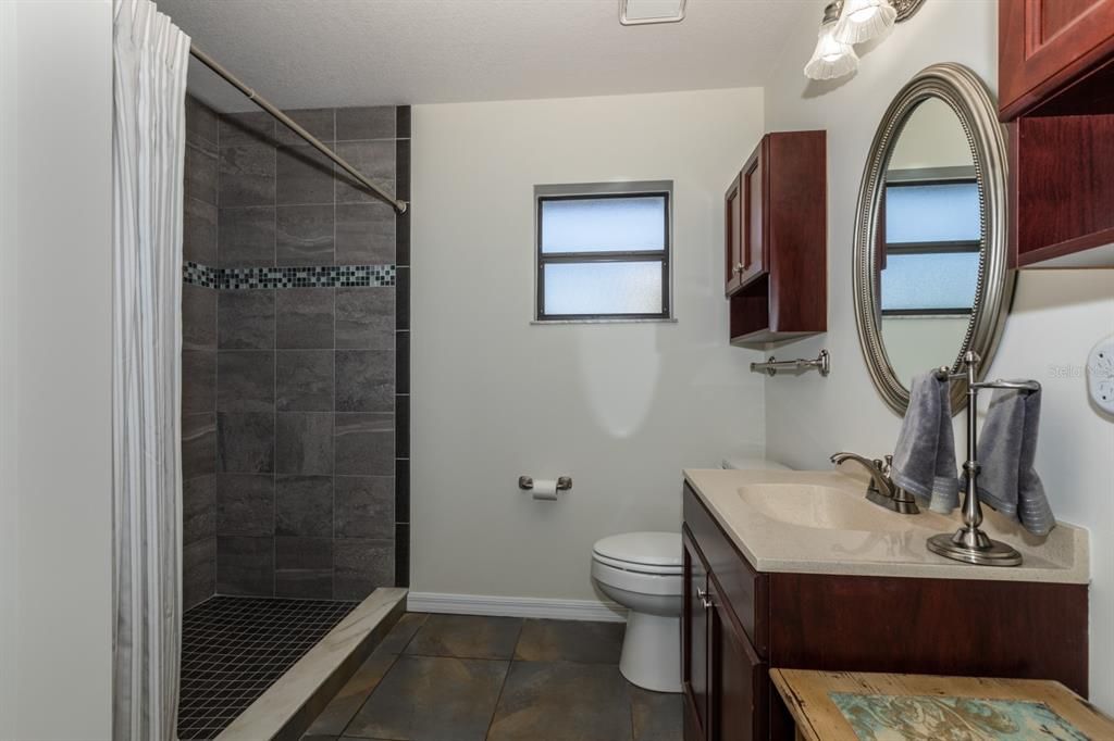 Oversized bathroom with beautiful floor to ceiling tile shower.