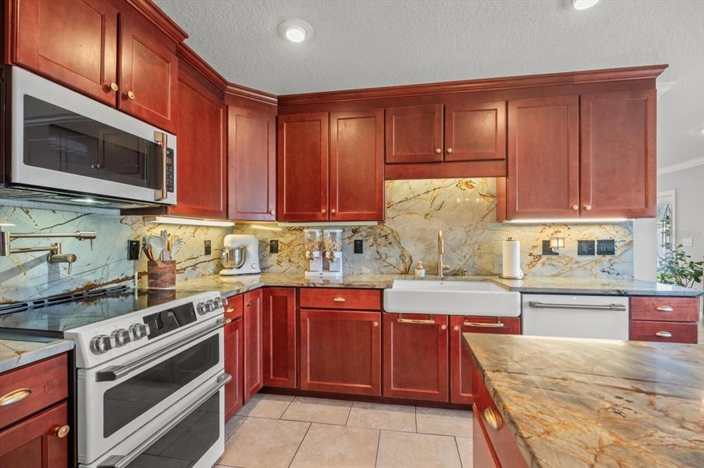 Kitchen view: Cafe kitchen appliances; White stainless with Rose gold trim, Granite counters and backsplash, tile flooring