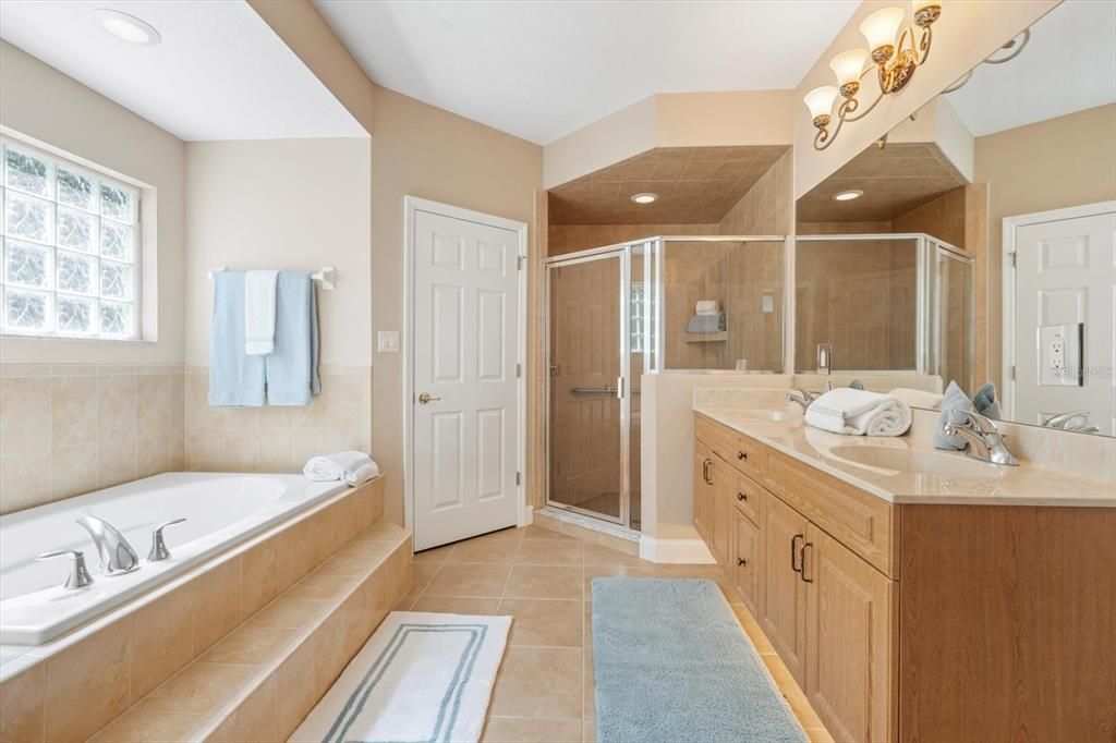 Primary bathroom: step up soaking tub, tile walk in showerWalk in closet and double vanity,glass block window