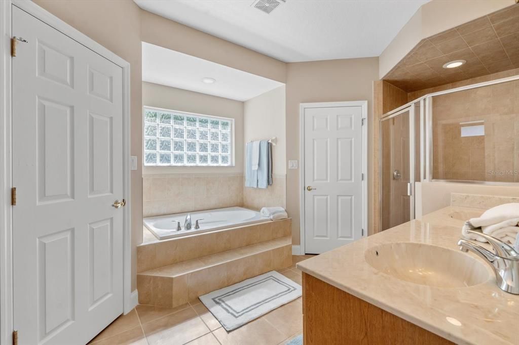 Primary bathroom: step up soaking tub, tile walk in shower, Dual Walk-in closets and double vanity, glass block window