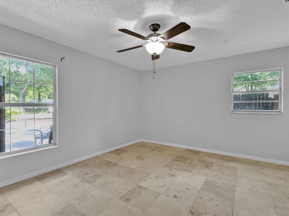 Primary bedroom 13'x14' with Travertine floors, large closet, & ceiling fan overlooks the backyard.
