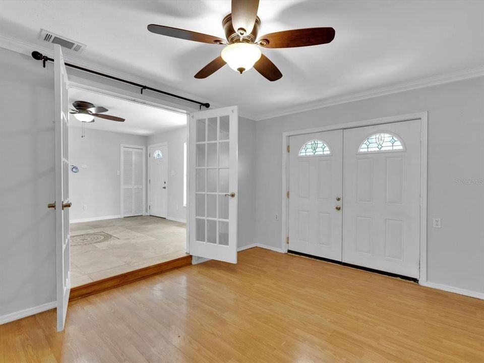 Bonus room 14'x10' with closet, ceiling fan, crown molding, french doors leading to the living room and double door access outside.