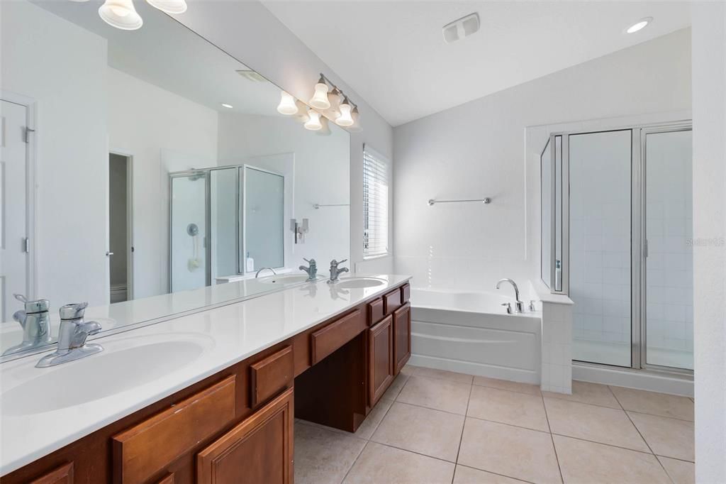 The ensuite bath featuring dual sinks, a rejuvenating garden tub, separate shower, and a generously sized walk-in closet