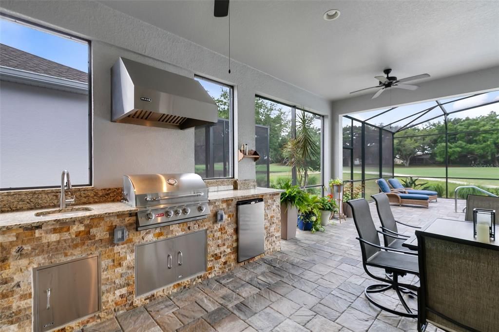 Outside, the extended lanai features an amazing summer kitchen with a grill, fridge, and sink, making it an entertainer's dream.