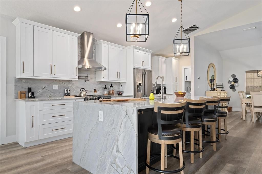 Kitchen with solid wood soft close cabinets, waterfall quartz on both sides of island and follow through with backsplash for a cohesive look and feel