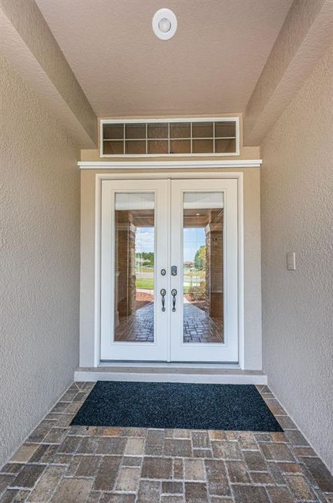 Paver front porch with beautiful glass entry doors.