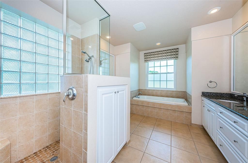 Glass enclosed tile shower with bench seat.