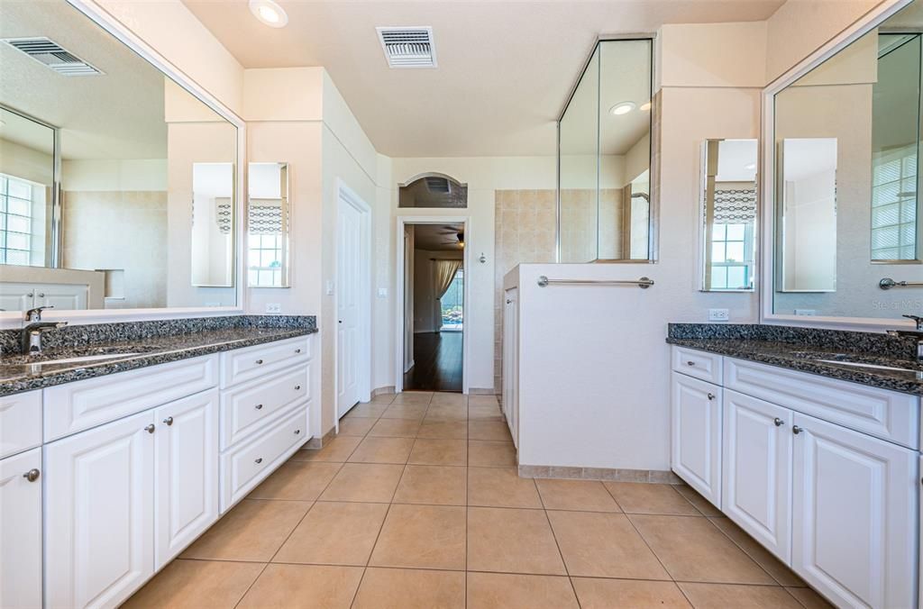Luxurious primary bath has private water closet and his and her vanities.