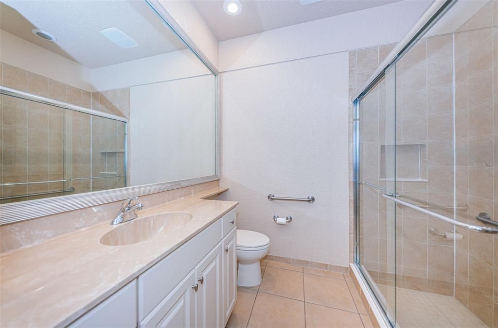 Full bathroom with refaced cabinets, Toto Toilet and glass shower doors opens to lanai and pool.
