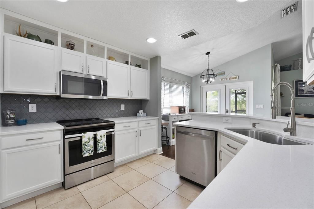 The home chef will be delighted with the chic color palette, STAINLESS STEEL APPLIANCES, cabinetry that extends to the ceiling, decorative backsplash, QUARTZ COUNTERS and a breakfast bar for additional casual dining.