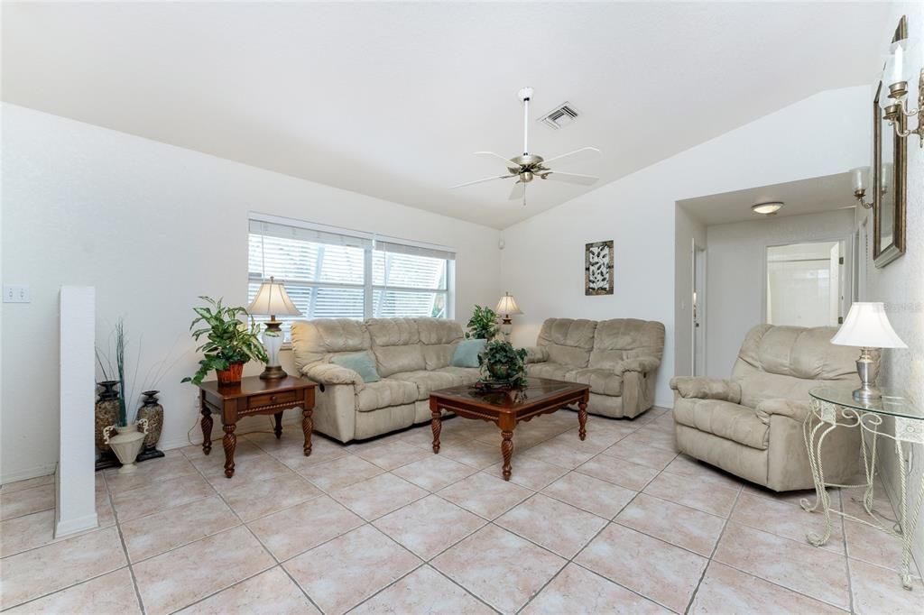 Living room has a cathedral ceiling and tiled flooring