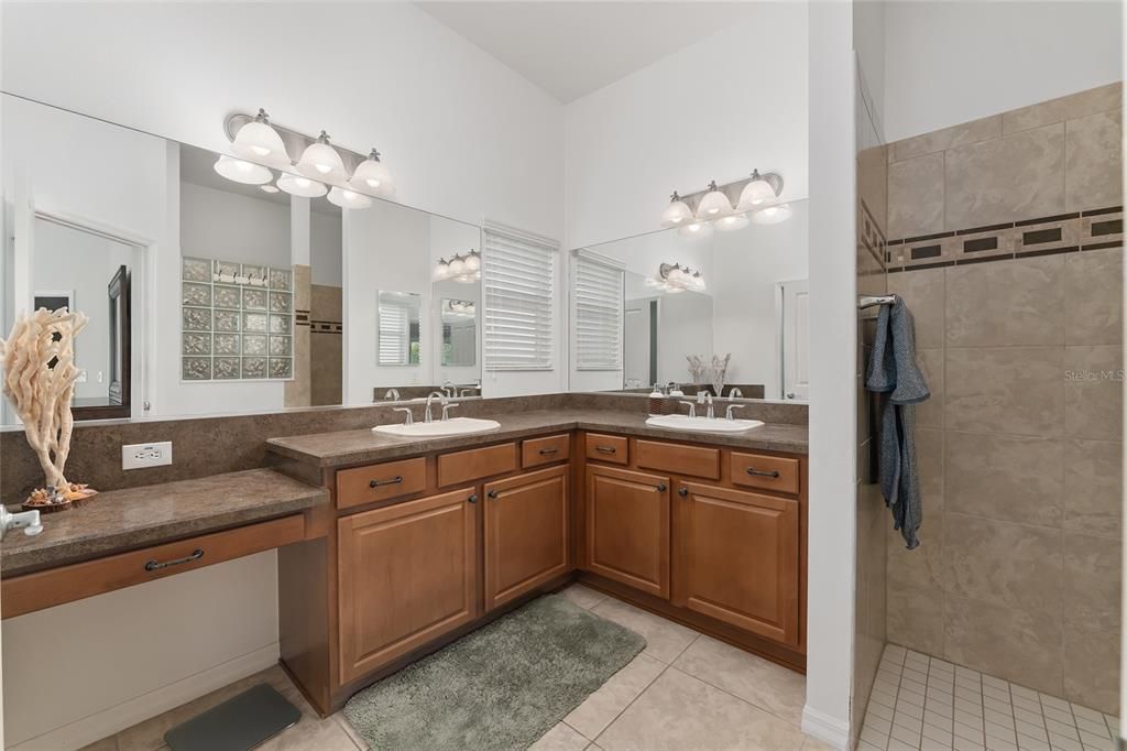 DOUBLE SINKS AND LOWERED VANITY SECTION WITH NICE LIGHTING AND WINDOW THAT PROVIDES NATURAL LIGHT