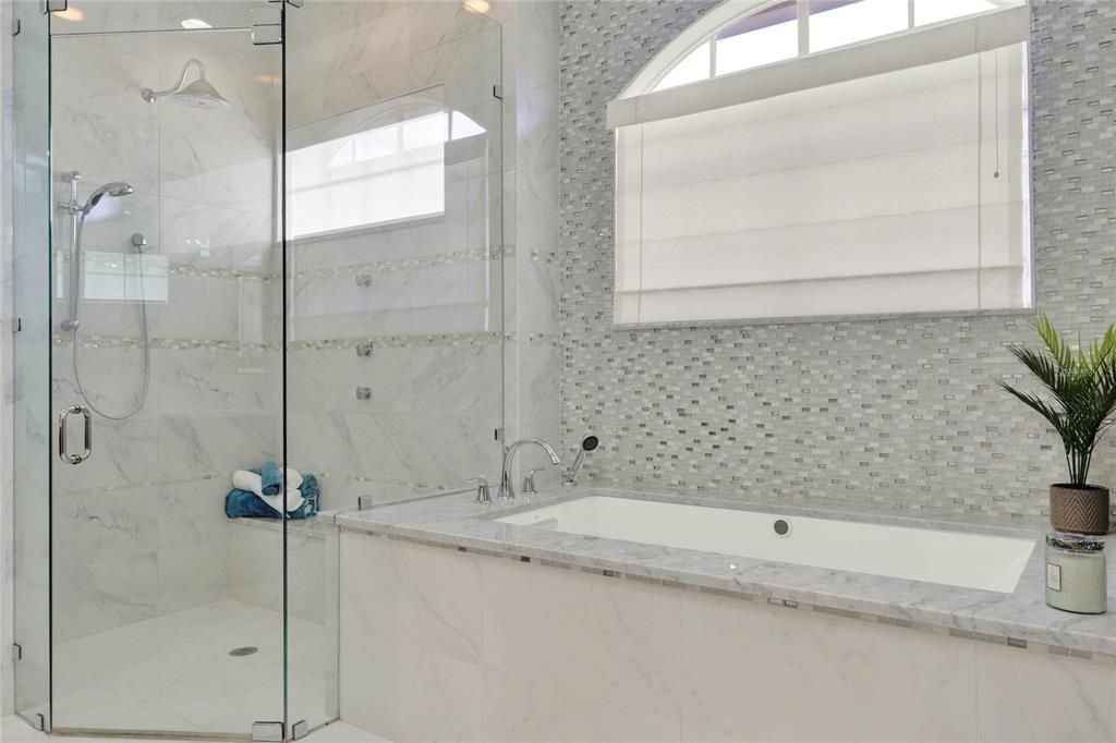 Frameless shower and separate soaking bathtub with decorative tile