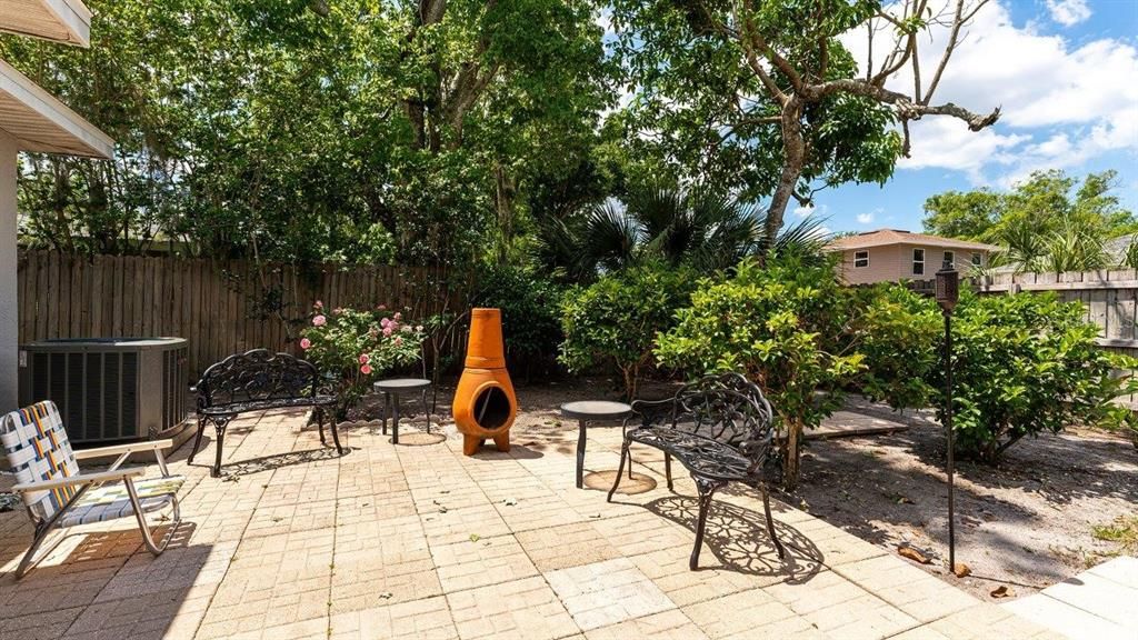 Extended paver lanai featuring a fire pit and beautiful landscaping.
