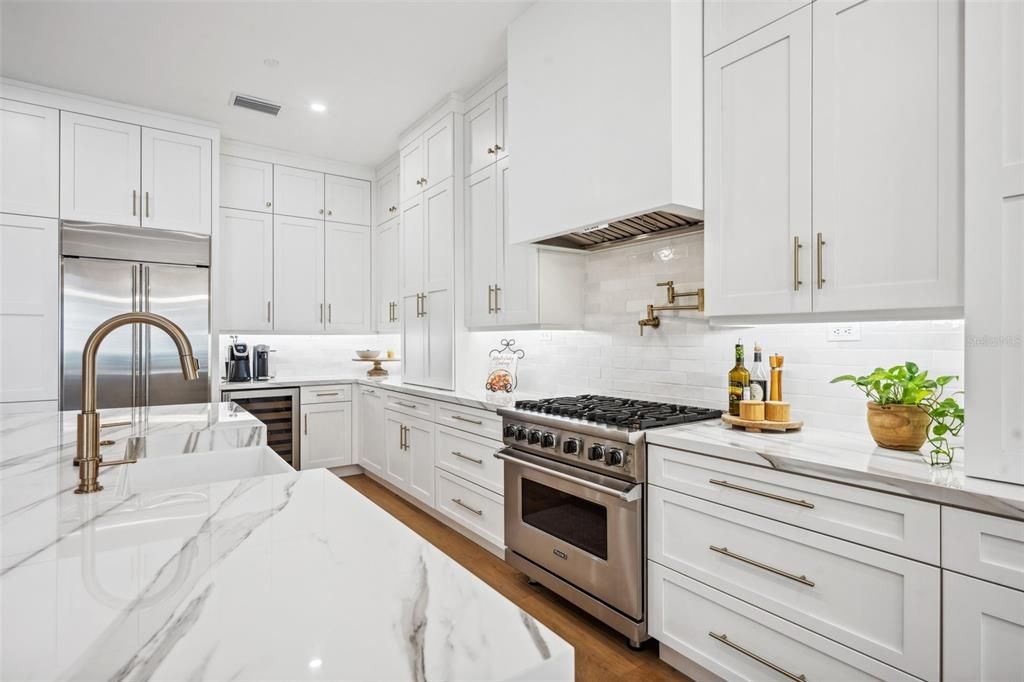 Dream kitchen features a Viking range & dishwasher, pot filler, wine refrigerator farm sink & under cabinet lighting