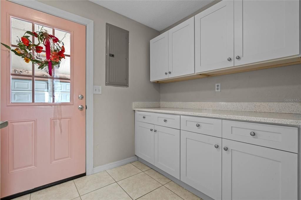 Back entrance to the home leading into the spacious laundry room with abundance of cabinets and counter space
