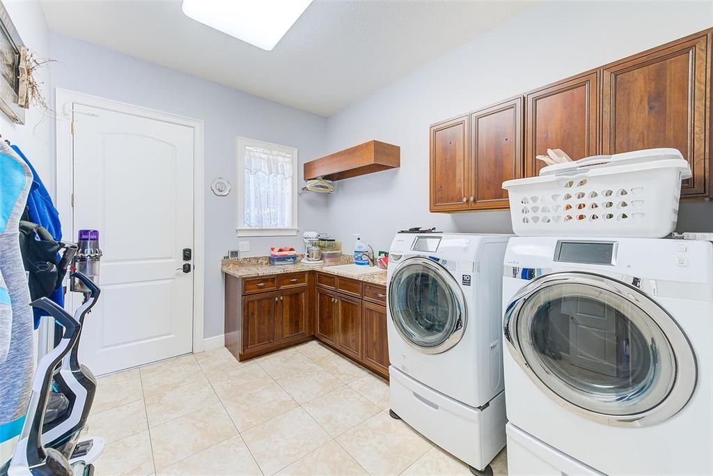 HUGE LAUNDRY SUITE WITH CABINETRY & FOLDING STATION INCLUDING UTILITY SINK