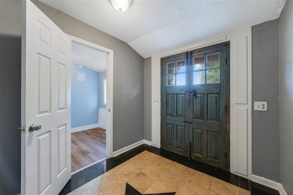 Or DOUBLE ANTIQUE DOORS from France to the side open up to a comfortable foyer with another flex space to the right for a cozy den or home office.