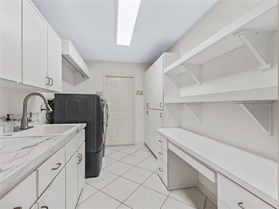 Laundry room with sink, desk and lots of cabinets.